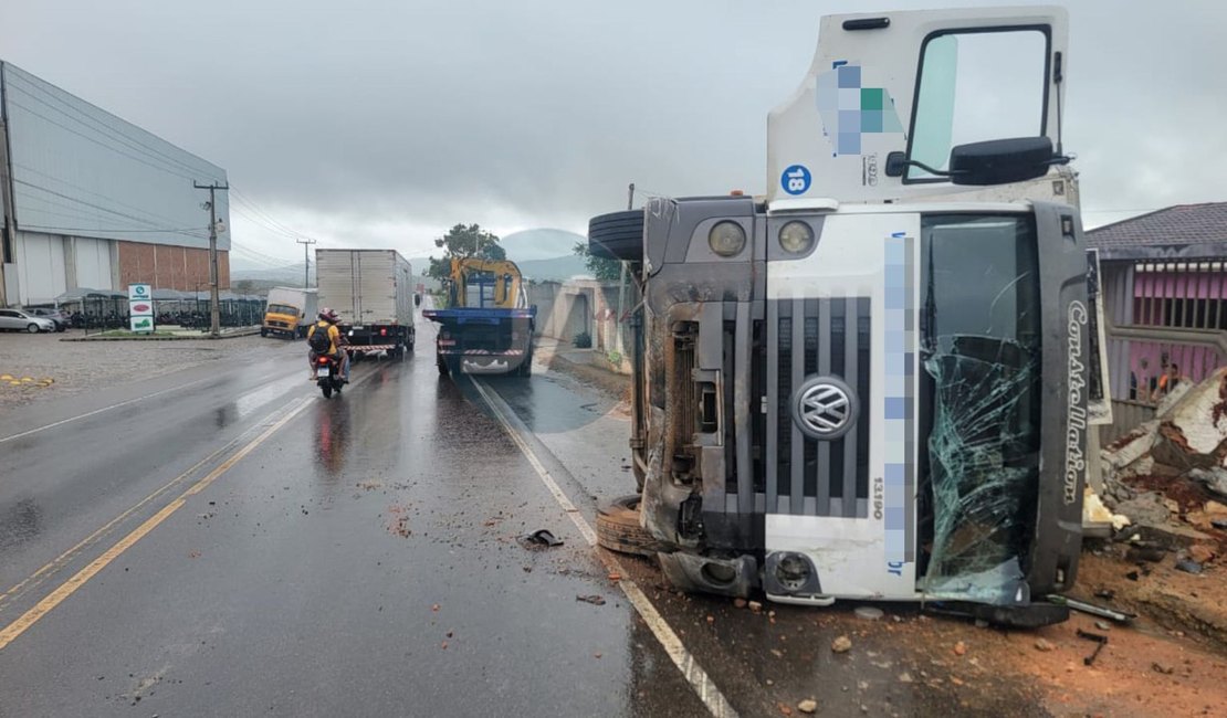 Caminhão de distribuidora tomba e derruba muro de residência na AL-110, em Arapiraca; motorista ficou ferido