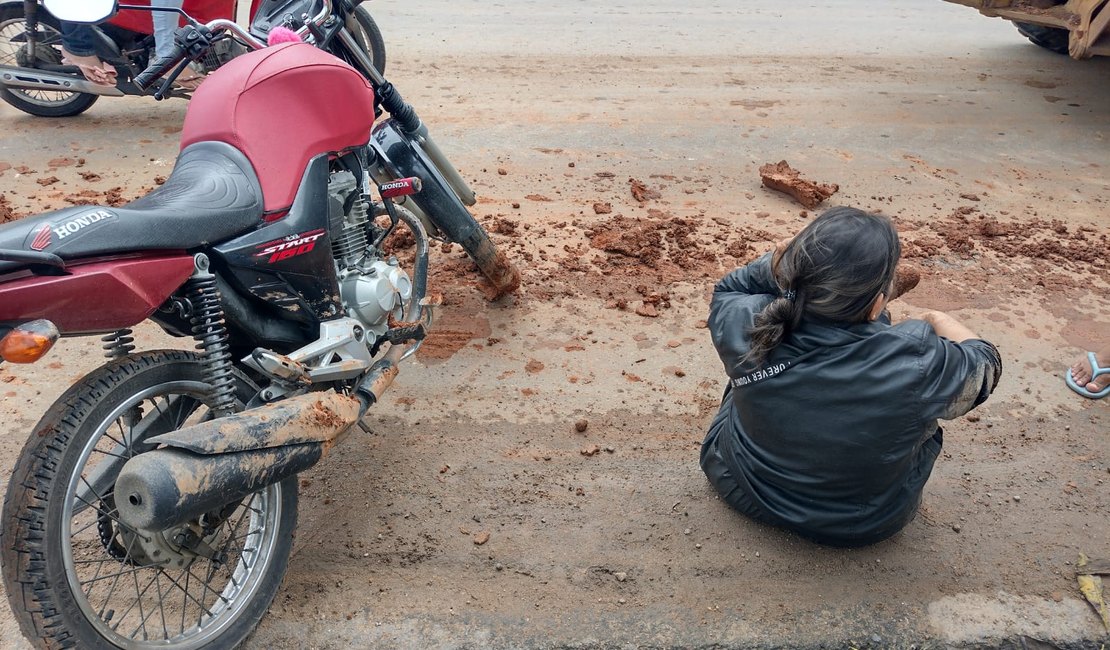 Mulher fica ferida após derrapar moto em barro e cair na rua em