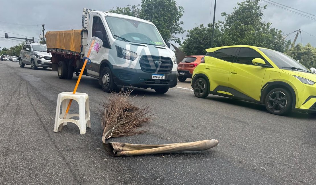 Populares sinalizam rua com galhos e bancos para evitar acidentes, após derramamento de diesel, em Arapiraca