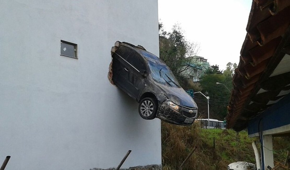 Motorista acelera em garagem e carro fica pendurado fora do prédio