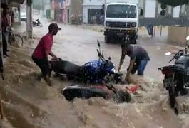 Homens tentam impedir que motos sejam levadas pela água durante temporal em São Sebastião; ASSISTA