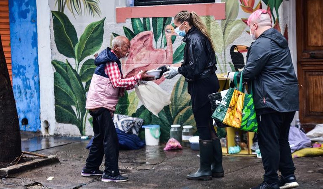 Debaixo de chuva, Adriane Galisteu entrega marmitas para pessoas que moram nas ruas de SP