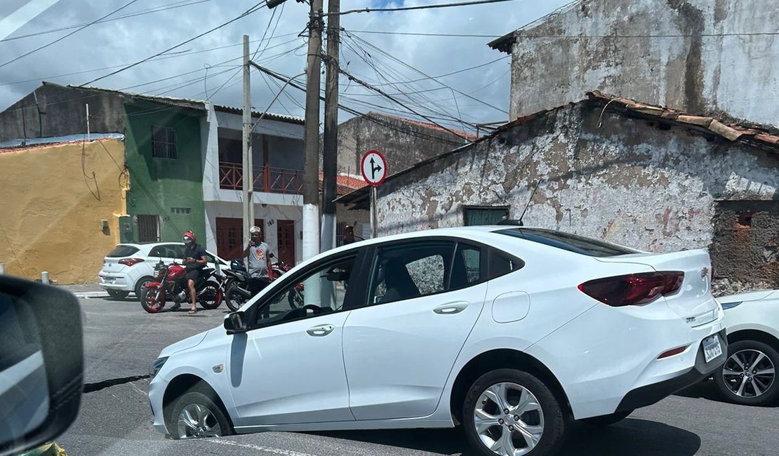 Asfalto cede e parte frontal de carro vai parar dentro de cratera em Maceió