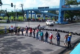 Grupo de manifestantes com rostos cobertos bloqueia a BR-104, na entrada da UFAL em Maceió