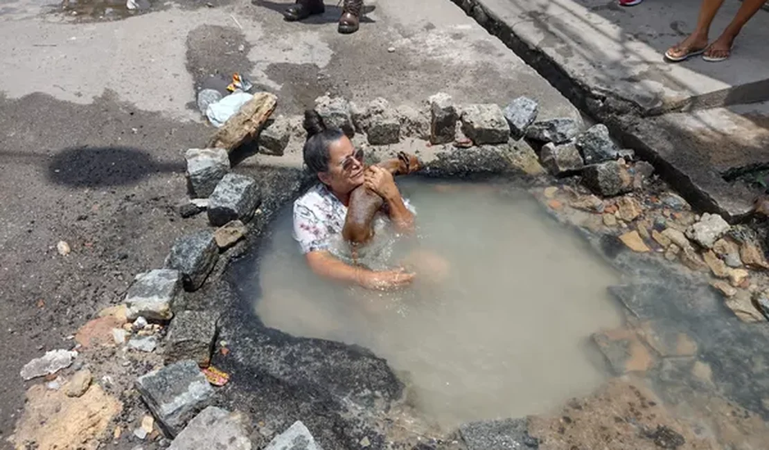 Idosa toma banho em buraco para protestar contra falta de água e vazamento no Grande Recife