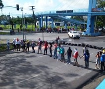 Grupo de manifestantes com rostos cobertos bloqueia a BR-104, na entrada da UFAL em Maceió