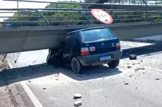 Motorista morre após caminhão bater em passarela e estrutura cair sobre carro