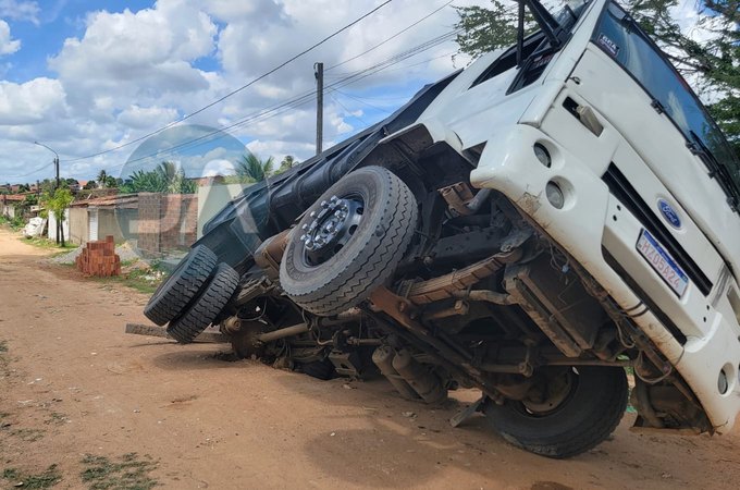 Pneu de caçamba carregada de areia fica presa em buraco, em Arapiraca