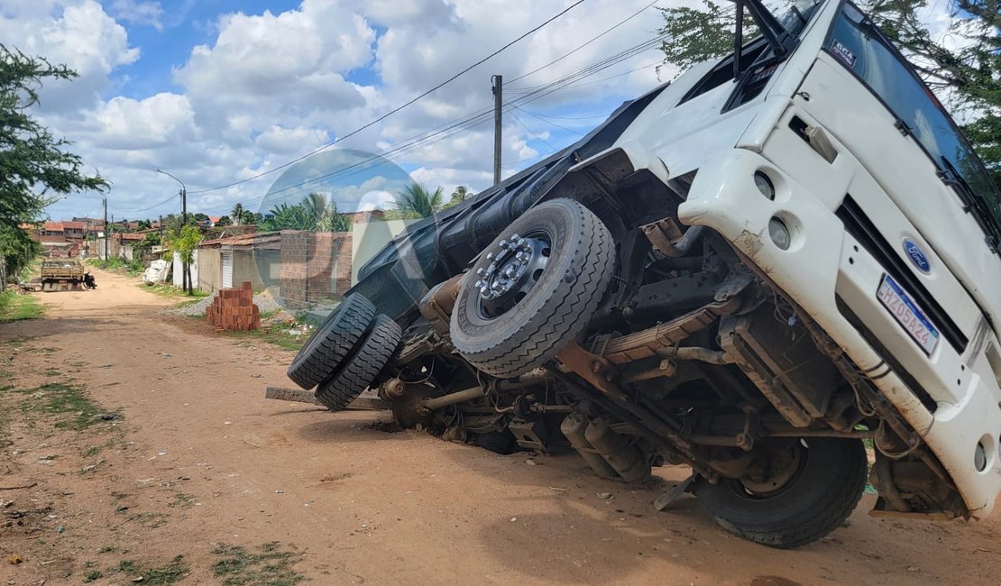 Pneu de caçamba carregada de areia fica preso em buraco, em Arapiraca