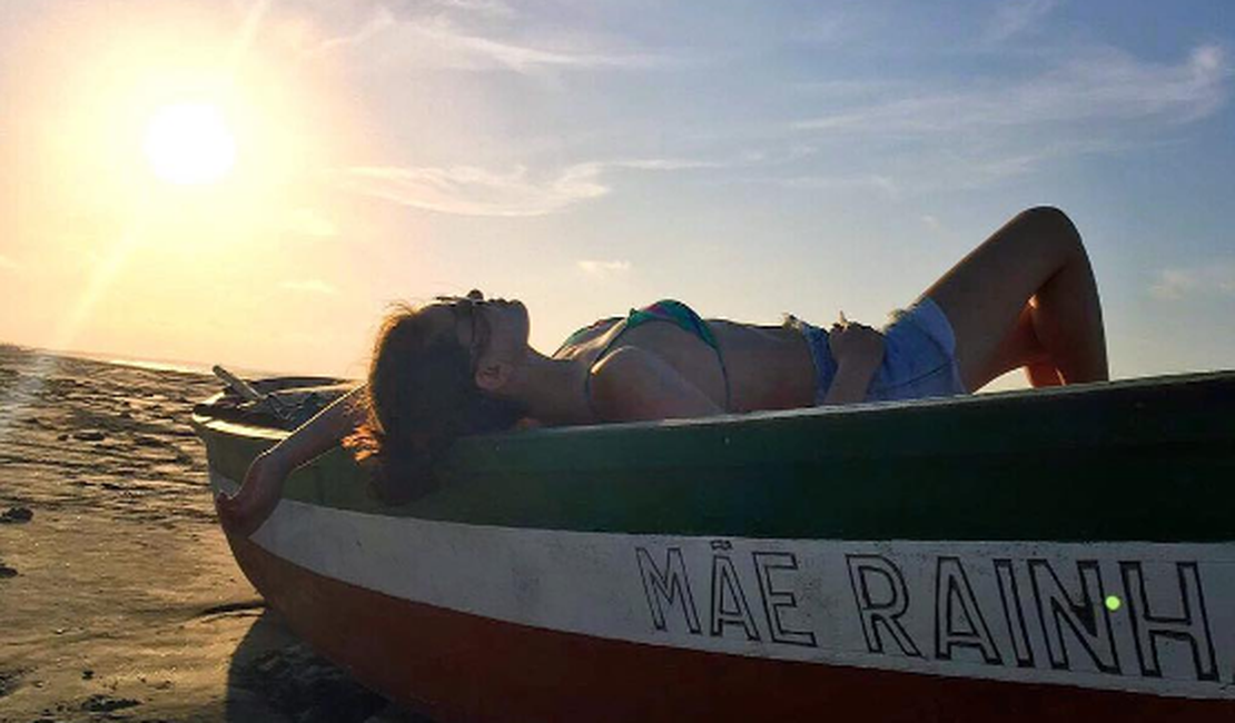 Camila Queiroz relaxa em proa de barco durante passeio em praia