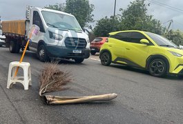 Populares sinalizam rua com galhos e bancos para evitar acidentes, após derramamento de diesel, em Arapiraca