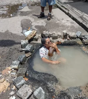 Idosa toma banho em buraco para protestar contra falta de água e vazamento no Grande Recife