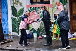 Debaixo de chuva, Adriane Galisteu entrega marmitas para pessoas que moram nas ruas de SP